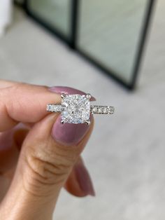 a woman's hand holding an engagement ring with a diamond on the middle and side