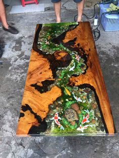 a man standing next to a table made out of wood and glass with koi fish on it