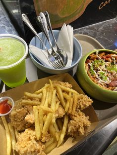 some food is sitting on a table next to two bowls with drinks and silverware