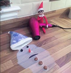 an elf is sitting on the floor next to a hair dryer and some cookies