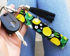 a person holding a keychain with lemons on it and a black tassel