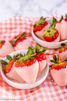 strawberries are arranged in heart shaped bowls on a checkered tablecloth