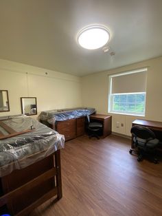 an empty bedroom with two beds, desks and a chair in it's corner