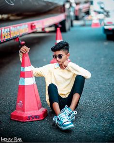 a young boy sitting on the ground next to a traffic cone