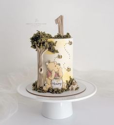 a winnie the pooh themed birthday cake on a white plate with trees and honeycombs