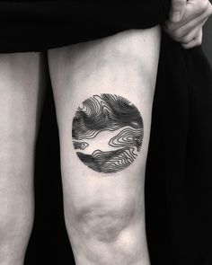 a black and white photo of a woman's legs with an abstract wave tattoo