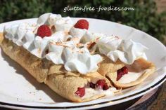 a white plate topped with a pastry covered in whipped cream and raspberries