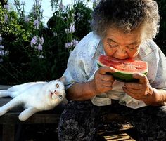 an older woman sitting on a bench with a watermelon slice