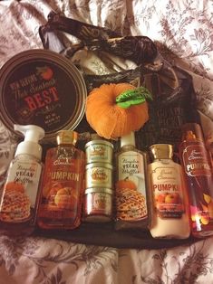 the contents of an autumn gift bag laid out on a bed with pumpkins and spices