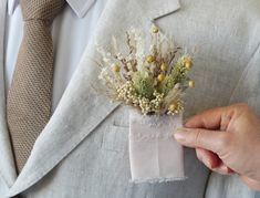 a man wearing a suit and tie holding a boutonniere with flowers in it