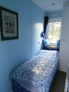 a small bedroom with blue walls and a bed