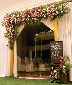 an entrance to a restaurant decorated with flowers and greenery for a wedding ceremony or reception