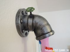 a metal faucet mounted to the side of a wall next to a pink vase