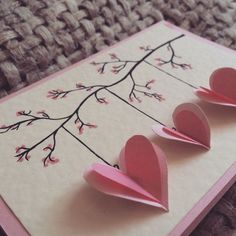 two paper hearts are placed on top of a card that is folded to look like flowers