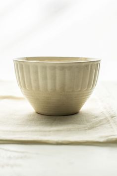 a white bowl sitting on top of a table next to a napkin and spoon in front of it