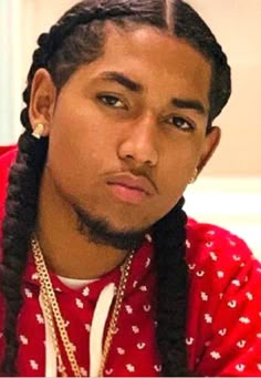 a man with long braids wearing a red shirt and gold chains on his neck