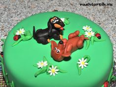 a green cake decorated with animals and daisies