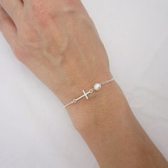 SOLID STERLING SILVER PARTS - A QUALITY BRACELET This lovingly hand-made bracelet is crafted using a solid sterling silver cross that measures just under 3/4 inch long. A 6mm Swarovski pearl comes in your choice of 5 colors. The sturdy sterling silver chain and lobster clasp make this a durable bracelet. Comes in a gift box. SIZING - IMPORTANT: To determine bracelet size, measure snugly around your wrist and add 1/2 inch to get your bracelet size. Do NOT order in your exact wrist measurement. Silver Cross Bracelets For Gifts, Minimalist Sterling Silver Cross Bracelet, Dainty Sterling Silver Cross Bracelet, Nickel Free Silver Cross Bracelets, Nickel Free Sterling Silver Cross Bracelets, Silver Bracelet With Cross Pendant As Gift, Nickel-free Cross Bracelet Gift, Silver Cross Bracelet, Spiritual Style, Nickel-free Silver Cross Bracelets