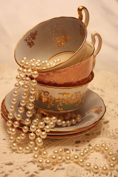 a stack of tea cups and saucers with pearls