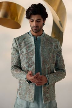 Chateau Delight Short Jacket | Jatin Malik Introducing our exquisite chateau grey hand-embroidered short jacket set, a true work of art. Crafted using the traditional zardozi technique, this beautiful piece is adorned with multicolor embroidery. The second tier features intricate highlighting with 3D brass elements, dabka, and zari threads, adding depth and sophistication to the design. Paired with a matching short-length kurta and tapered trousers, this ensemble embodies refined elegance and impeccable craftsmanship, perfect for making a statement at any special occasion. Included in purchase: Short Jacket, Kurta, Trousers Product Specification Color: Chateau Grey Fabric: Linen Silk Occasion: Engagement, Wedding, Bridal, Reception Style: Short Jacket, Kurta, Trousers Care: Dry Clean Work: Silk Nehru Jacket With Intricate Embroidery For Reception, Long Sleeve Outerwear With Intricate Embroidery For Reception, Elegant Silk Nehru Jacket With Floral Embroidery, Long Sleeve Nehru Jacket With Intricate Embroidery For Reception, Fitted Embroidered Outerwear For Reception, Embroidered Fitted Outerwear For Receptions, Embroidered Fitted Outerwear For Reception, Silk Outerwear With Intricate Embroidery For Festive Occasions, Embroidered Silk Outerwear For Wedding