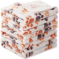 a stack of orange and white towels with paw prints on the front, one is folded in half