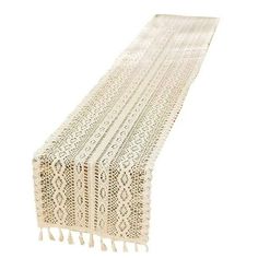 a white table runner with tassels on it