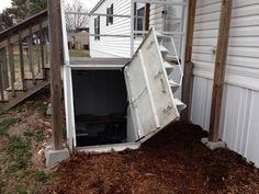 an open refrigerator sitting in the middle of a pile of mulch next to a house