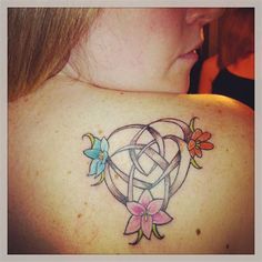 a woman with a tattoo on her back shoulder and flowers around the neck is looking at the camera