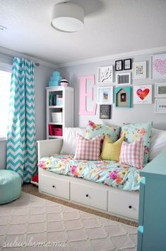 a white day bed sitting under a window next to a blue and pink wall with pictures on it