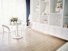 a white table and chairs in a room with bookshelves on the wall behind it