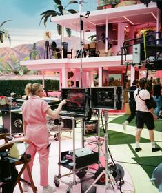 a woman standing in front of a pink building with lots of equipment on it's sides