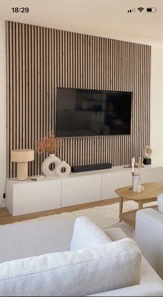 a modern living room with striped wallpaper and white sofas in front of the flat screen tv