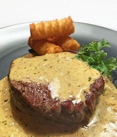 a steak with gravy and fries on a plate