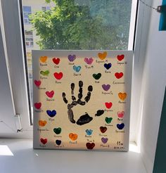 a handprint is displayed in front of a window with many hearts on the outside