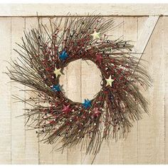 a wreath with red, white and blue stars hanging on a wooden wall next to a door