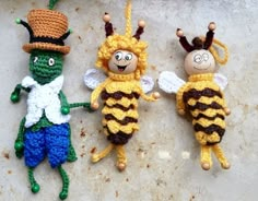 three crocheted bees are laying on the ground with one wearing a top hat