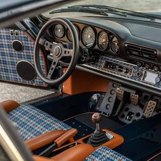 the interior of an old car with blue and brown leather seats, steering wheel and dashboard