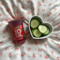 cucumber slices in a bowl next to a cup of yogurt on a bed