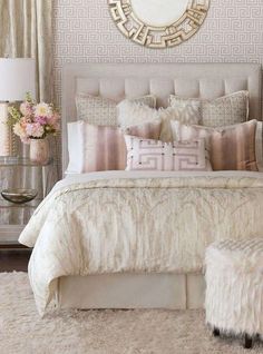 a white bed with pillows and blankets in a bedroom next to a mirror on the wall