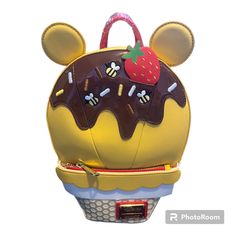 Loungefly Disney Winnie The Pooh Ice Cream Backpack Satisfy The Rumble In Your Tummy With A Scoop Of Something Scrumptious! This Exclusive Loungefly Winnie The Pooh Ice Cream Figural Backpack Takes The Form Of A Delectable Delicacy. On The Front, A Figural Ice Cream Scoop Is Covered In Chocolate Syrup And Embroidered Sprinkles As It Sits Atop A Waffle Cone Base. Take A Closer Look And You’ll Find Hints To Our Favorite “Silly Ol’ Bear,” Including Honeybees, Ears, And A Strawberry Recalling The Co Disney Yellow Bags For Everyday Use, Disney Yellow School Bag, Yellow Disney School Bag, Cute Yellow Travel Backpack, Fun Yellow Backpack Bag, Fun Yellow Backpack, Loungefly Purse, Loungefly Bag, Loungefly Disney