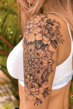 a woman's arm with flowers and leaves tattooed on the back of her shoulder