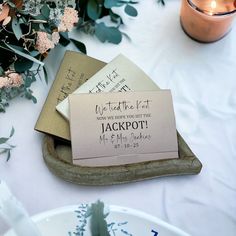 two wedding cards sitting on top of a table next to some flowers and candle holders