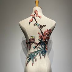 a white mannequin with flowers and birds painted on it's back side