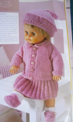 the doll is wearing a pink knitted sweater and hat with matching booties on it