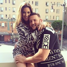 a man and woman hugging each other on a balcony