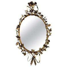 a mirror that has some flowers on the frame and is hanging from it's side