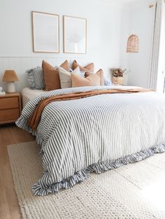 a large bed sitting next to a window on top of a wooden floor covered in pillows