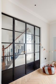 an empty room with black glass doors and wooden flooring on the other side of the door