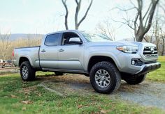 a silver truck parked on top of a lush green field