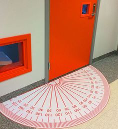 an orange door with a large ruler on the floor in front of it and a red door